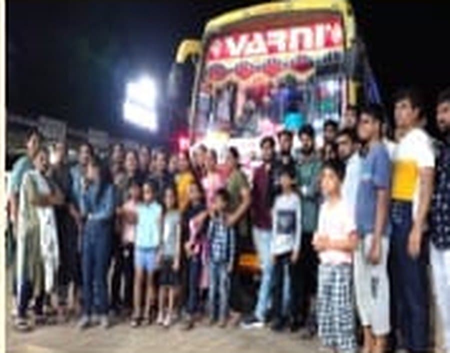 Travellers gathered beside a Varni coach before a night departure